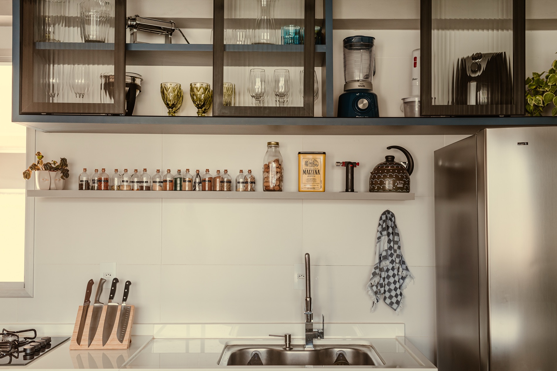 Detalhe de cozinha com armários e prateleira, projeto do Estúdio Leme