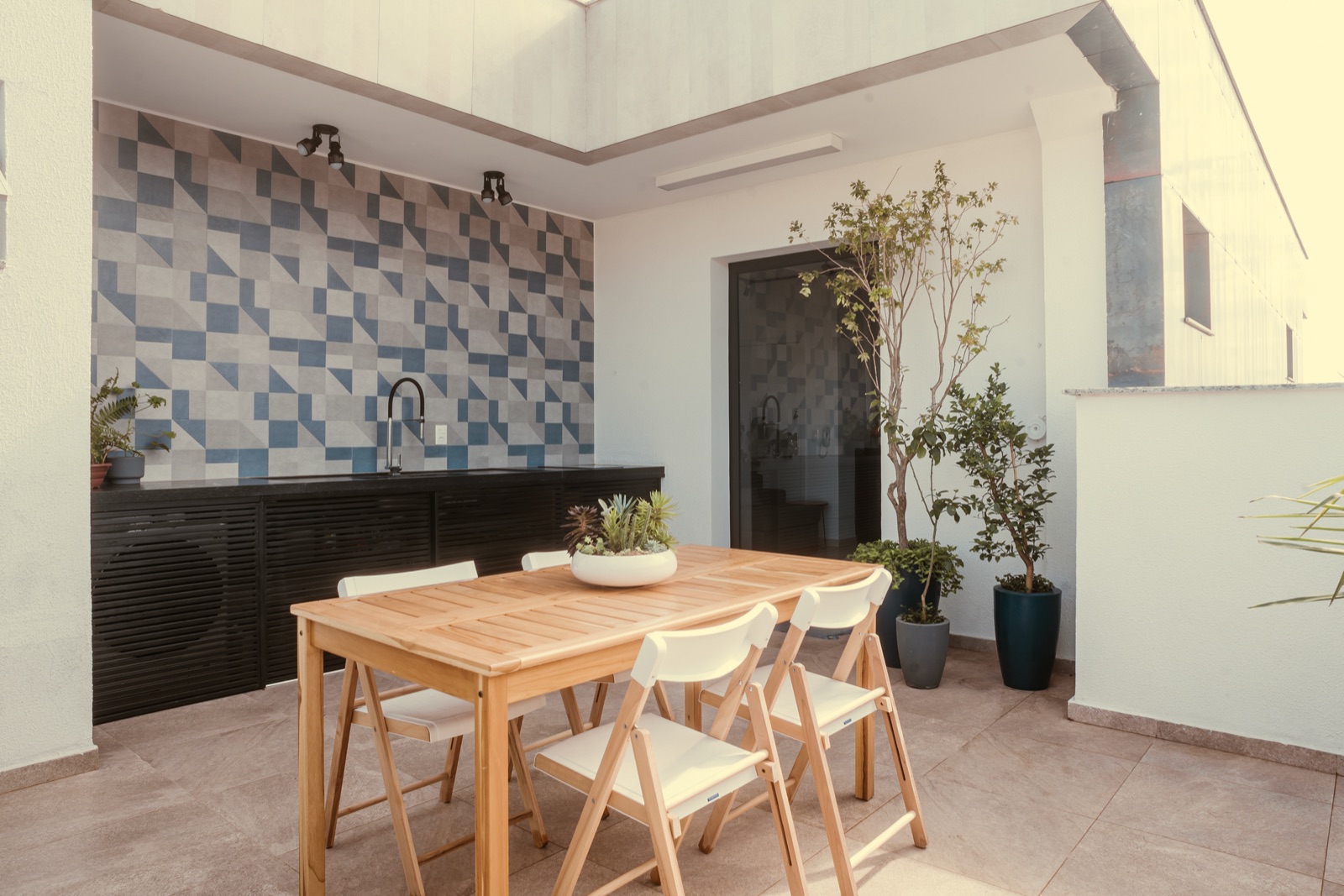 Área gourmet com mesa de madeira e parede de azulejos